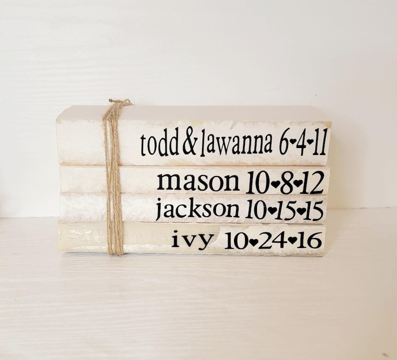 May include: A stack of white books with black text. The books are tied together with twine. The text on the books reads: "todd & lawanna 6-4-11", "mason 10-8-12", "jackson 10-15-15", and "ivy 10-24-16".