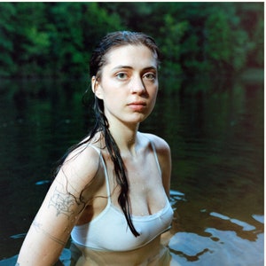 Może przedstawiać: Okładka albumu "Older" Lizzy McAlpine. Okładka przedstawia kobietę z mokrymi włosami, ubraną w biały top na ramiączkach, zanurzoną w wodzie. Tytuł albumu "Older" jest wyświetlany u góry okładki, a imię artystki "Lizzy McAlpine" jest wyświetlane dużymi, pogrubionymi literami pod obrazem. Lista utworów albumu jest wymieniona pod nazwą artystki, wraz z rokiem wydania albumu, liczbą utworów i całkowitym czasem trwania.