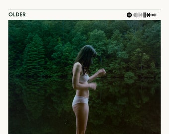 May include: Album cover art for the album "Older" by Lizzy McAlpine. The cover features a woman standing in a lake, with a forest in the background. The album title is written in large, white letters at the bottom of the image. The album title is "Older" by Lizzy McAlpine. The album has 14 songs and is 45 minutes long.