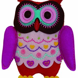 May include: A plush owl toy with a red body, purple wings, and a brown face with embroidered eyes. The owl has a pink, green, and yellow patterned design on its chest.