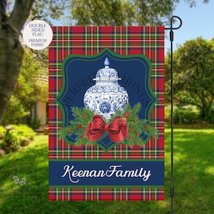 May include: Double-sided garden flag with a blue and white porcelain jar design, red bow, and green pine branches on a navy blue background. The flag has a red, green, and blue plaid pattern and the text "Keenan Family".