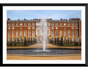 May include: A large, red brick building with a fountain in front of it. The building has many windows and a symmetrical design. The fountain is tall and narrow, with water spraying high into the air.