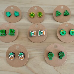 Puede incluir: Conjunto de 10 pares de pendientes temáticos de San Patricio en verde y dorado. Los pendientes presentan tréboles, duendes, ollas de oro, banderas y nudos celtas.