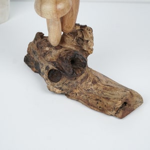 Puede incluir: Una escultura de hongo de madera con un acabado marr&oacute;n y tostado, de pie sobre un trozo de madera a la deriva con veta de madera natural.