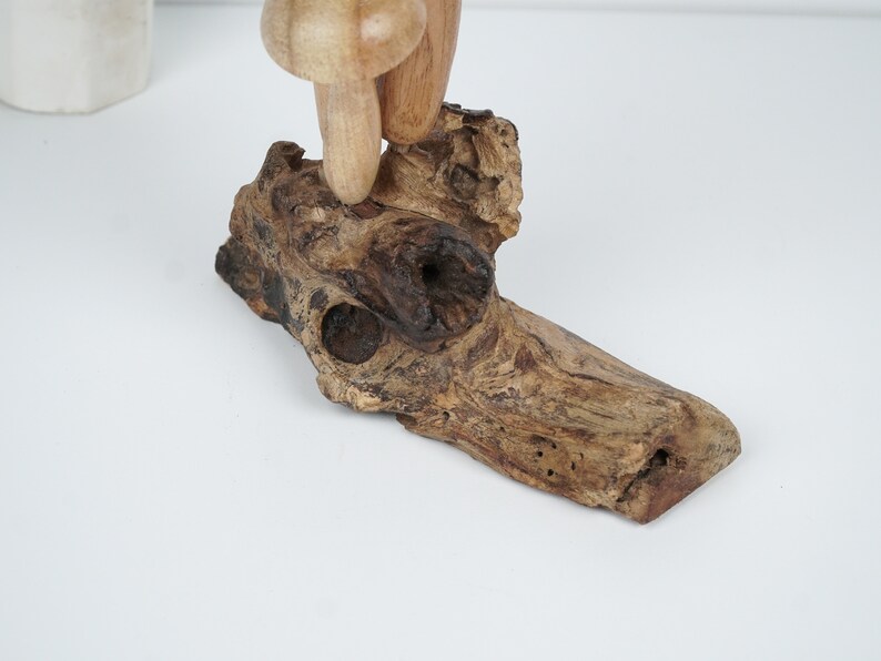 Puede incluir: Una escultura de hongo de madera con un acabado marr&oacute;n y tostado, de pie sobre un trozo de madera a la deriva con veta de madera natural.