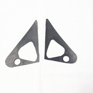 May include: Two black metal triangular shaped pieces with a smaller triangle cut out in the center of each piece. Each piece has a round hole in the bottom corner.