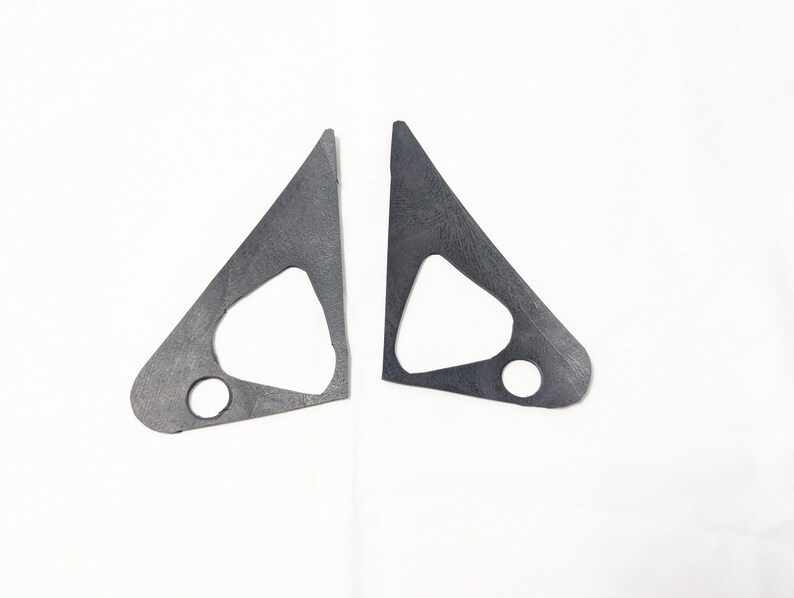 May include: Two black metal triangular shaped pieces with a smaller triangle cut out in the center of each piece. Each piece has a round hole in the bottom corner.