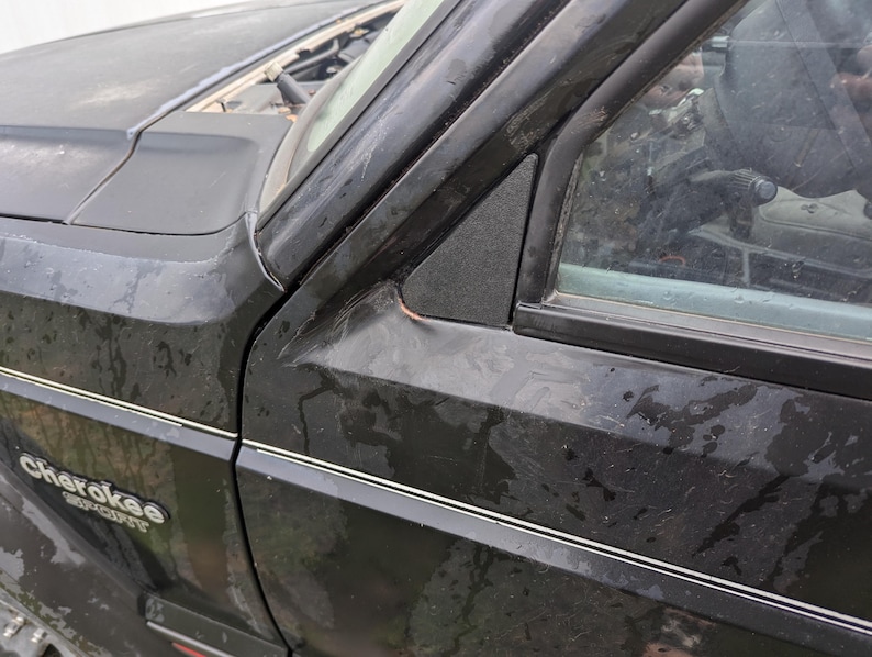 May include: A black Jeep Cherokee Sport with a silver trim around the windows and the words "Cherokee Sport" on the side.