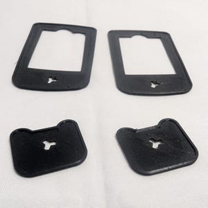May include: Four black, 3D-printed plastic components. Two are rectangular with a central opening and a small cutout at the bottom. The other two are square with rounded corners and a similar cutout. All are on a white surface.