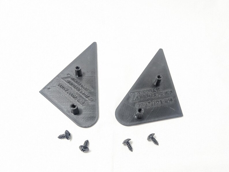 May include: Two black plastic triangle-shaped pieces with the text "Z-Axis Industries" and "Assembled in USA" on them. Four black screws are included.
