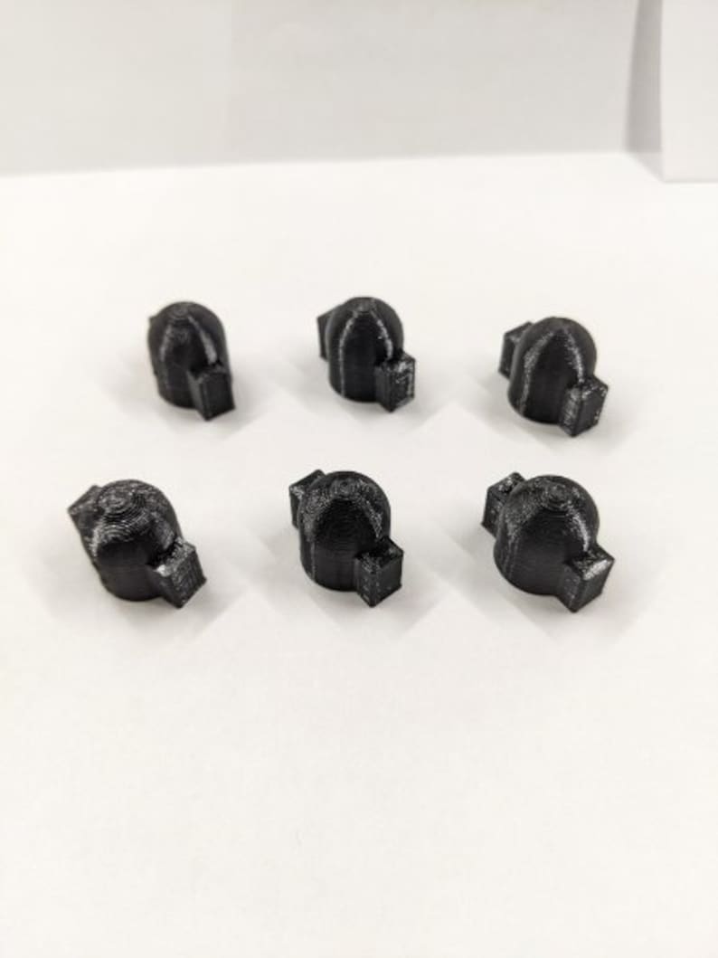 May include: Six black plastic knobs with a textured surface. The knobs have a rounded top and a flat bottom.