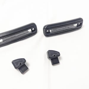 May include: Four black plastic pieces, two long rectangular pieces with a slot in the middle, and two smaller pieces with a rounded top.