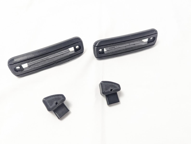 May include: Four black plastic pieces, two long rectangular pieces with a slot in the middle, and two smaller pieces with a rounded top.