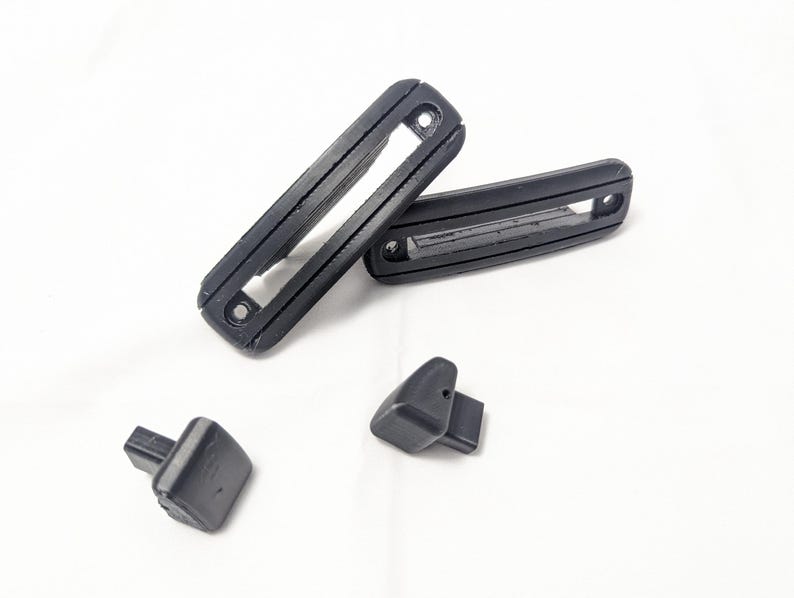 May include: Four black plastic pieces, two long rectangular pieces with a slot in the middle, and two smaller rectangular pieces.