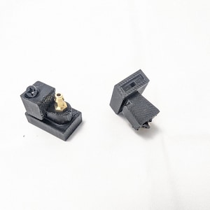 May include: Two black 3D printed plastic parts with a gold connector. One part has a screw on the side.