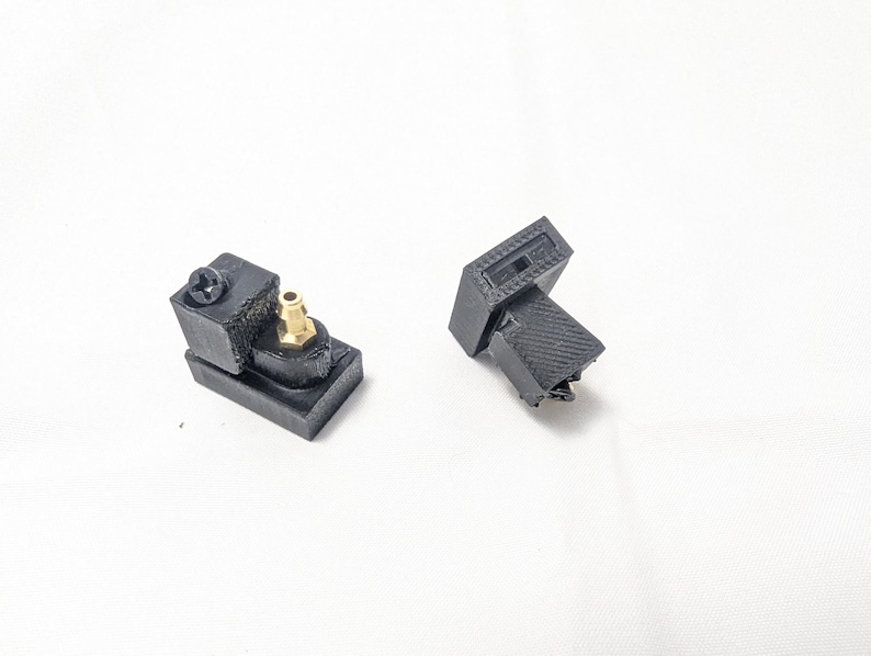 May include: Two black 3D printed plastic parts with a gold connector. One part has a screw on the side.