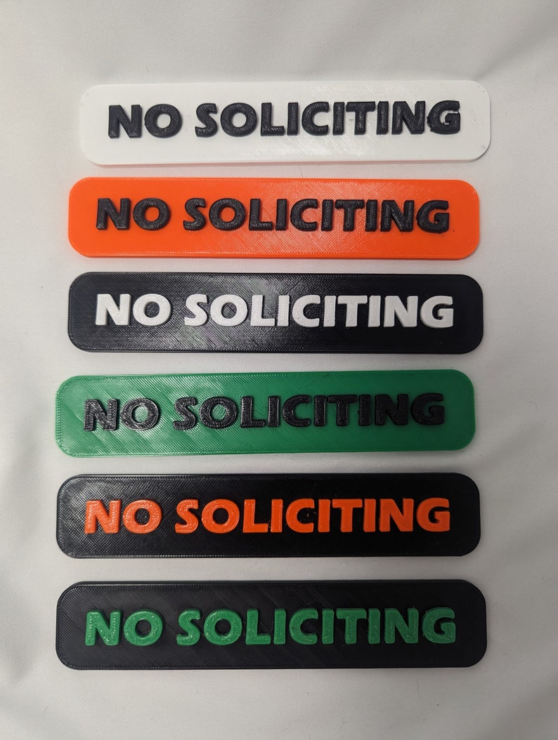May include: Six different color variations of a "No Soliciting" sign. The signs are rectangular and have a raised, black, 3D printed font.