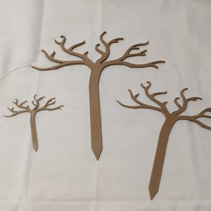May include: Three brown wooden tree silhouettes of varying sizes. The trees are made of wood and have a rustic, natural look. They are perfect for adding a touch of nature to any craft project.