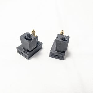 May include: Two black 3D printed parts with gold fittings. The parts are designed to be connected together.