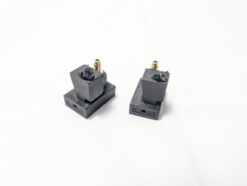 May include: Two black 3D printed parts with gold fittings. The parts are designed to be connected together.