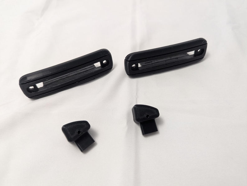 May include: Four black plastic pieces, two long rectangular pieces with a groove in the center, and two smaller pieces with a rounded top and a flat bottom.