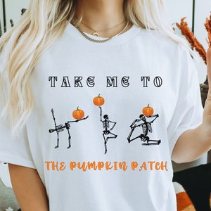 May include: White t-shirt with the text "Take me to the pumpkin patch" and a graphic of three skeletons holding pumpkins.