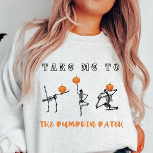 May include: A white sweatshirt with the text "Take Me To The Pumpkin Patch" and three skeletons holding pumpkins.