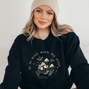 May include: Black sweatshirt with a graphic of a skull with mushrooms and butterflies. The text "It is well with my soul" is printed around the skull.