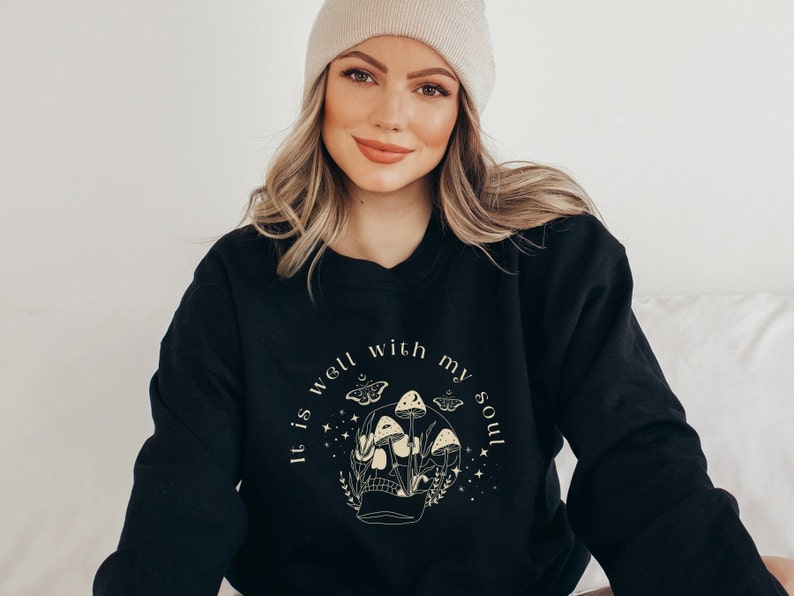 May include: Black sweatshirt with a graphic of a skull with mushrooms and butterflies. The text "It is well with my soul" is printed around the skull.