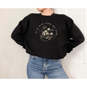 May include: Black sweatshirt with a graphic of a skull with mushrooms growing out of it. The text "It is well with my soul" is written around the skull.