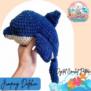 May include: A handmade crochet dolphin plushie featuring a deep blue upper body and a white underbelly. The toy has a smooth, soft texture with a prominent dorsal fin and a long tail. The text "Jumping Dolphin" and "Digital Crochet Pattern" appear.
