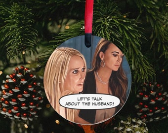 Peut inclure: Boule de Noël ronde avec une image de bande dessinée de deux femmes avec le texte "Parlons du mari !" dans une bulle de dialogue.