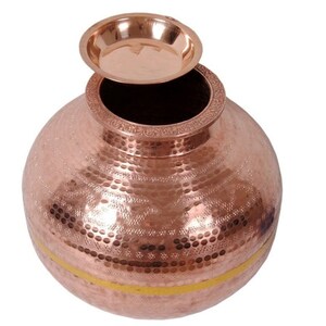 May include: A copper-colored, hammered metal pot with a small, matching plate resting on top. The pot has a rounded shape with a decorative band around the rim and a yellow stripe near the base. The surface is textured with a pattern of small indentations.