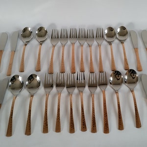 Puede incluir: Un juego completo de cubiertos con mangos de cobre martillado. El juego incluye cucharas, tenedores y cuchillos. Las cabezas de los utensilios son de acero inoxidable.