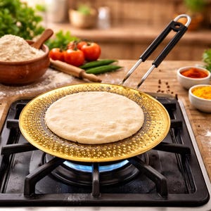 May include: A round, golden-colored griddle with a black handle is used to cook a flatbread over a gas stove. Ingredients like tomatoes, spices, and flour are in the background, suggesting a cooking scene. The griddle has a decorative dotted pattern.