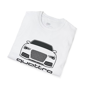 May include: White t-shirt with a black car outline and the word "Quattro" beneath. The shirt has a crew neck and the Audi logo is visible on the label.
