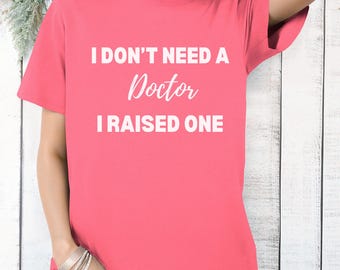 May include: Pink t-shirt with white text that reads "I don't need a Doctor I raised one".