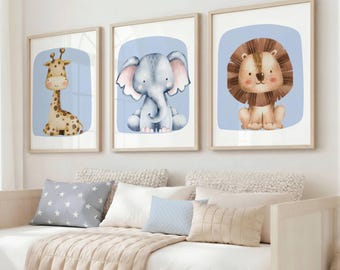 May include: Three framed wall art prints featuring watercolor illustrations of a giraffe, an elephant, and a lion. Each animal is centered on a light blue background within a white border, displayed in light-colored wooden frames on a wall.