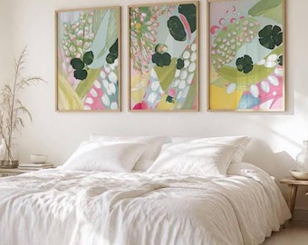 May include: Three rectangular framed wall art prints featuring abstract botanical patterns in shades of pink, green, yellow, and white. The artwork displays layered organic shapes, floral motifs, and foliage elements arranged in a vibrant composition.