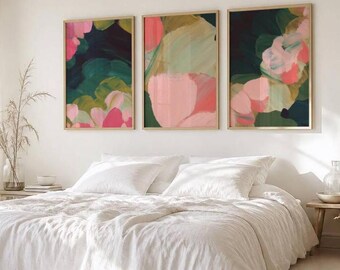 May include: A set of three rectangular wall art prints featuring abstract brushstrokes in shades of dark green, sage, soft pink, and coral. Each print is encased in a thin gold frame, displaying layered, organic shapes and blended color gradients.