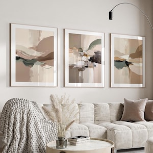 Könnte beinhalten: Drei gerahmte abstrakte Kunstdrucke. Jeder Druck zeigt eine sanfte Farbpalette aus Beige, Braun und gedämpftem Grün. Das Kunstwerk hat einen modernen, minimalistischen Stil, perfekt für die Inneneinrichtung. Die Rahmen sind hellholzfarben.