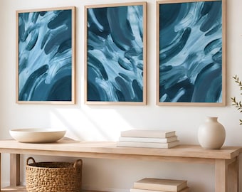 May include: Three rectangular wall art pieces in light wood frames featuring abstract brushstrokes in shades of deep navy, teal, and white. The artwork is displayed in a horizontal row, showcasing fluid, layered paint textures across each canvas.