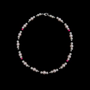 May include: A white pearl necklace with black and pink beads. The necklace has a silver clasp.