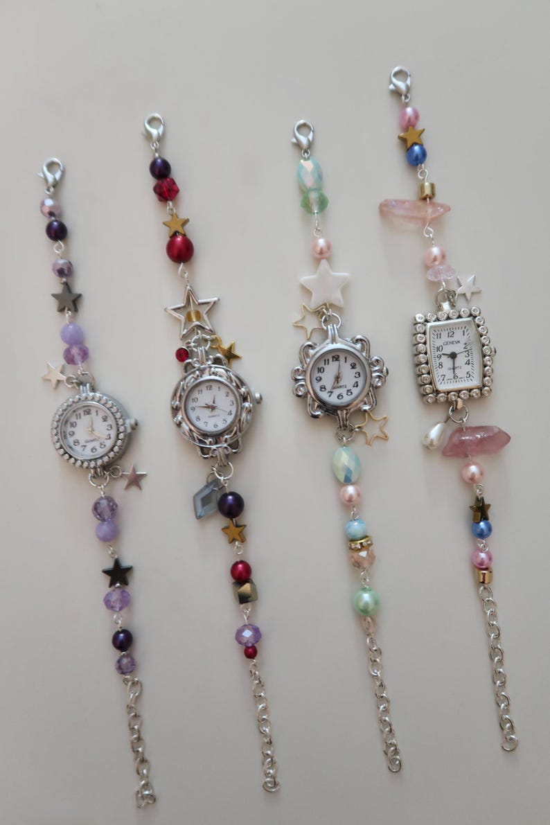May include: Four decorative watch charms with silver-toned watch faces and beaded chains. Each charm features a different watch face design, with colorful beads, stars, and other embellishments in shades of purple, red, pink, and gold.