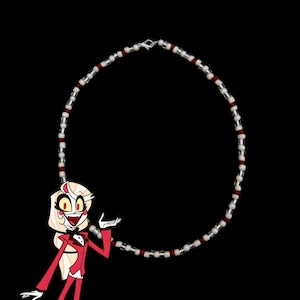 May include: A red and white beaded necklace with a silver clasp. The necklace is circular and has a repeating pattern of red and white beads.