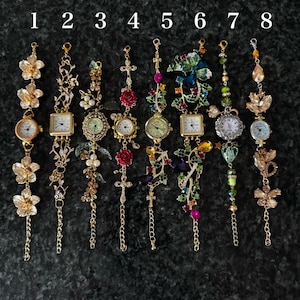 May include: Eight ornate, decorative wristwatches with various designs. Each watch features a different embellishment, including flowers, leaves, crosses, and gemstones. The watch faces are round or square, with Roman numerals. The watches are gold-toned and have delicate chains.