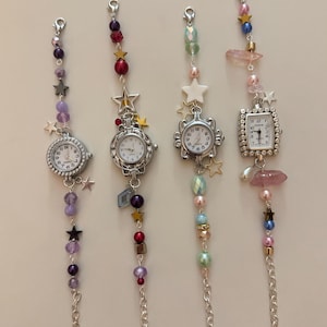 May include: Four decorative charm watches with silver-tone chains and beaded accents. Each watch features a different face shape and is adorned with colorful beads, stars, and crystals. The watch faces display the time.