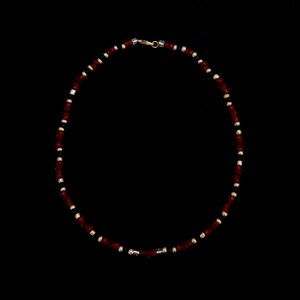 May include: A red and black beaded necklace with a gold clasp.