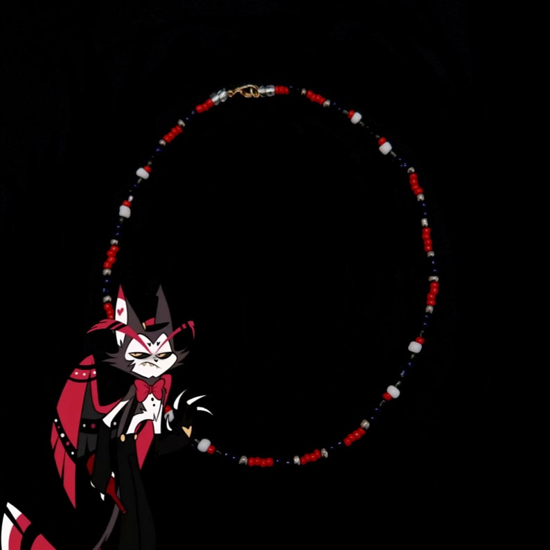 May include: A red, white, and blue beaded necklace with a silver clasp. The necklace is in the shape of a circle and is hanging from a black background. A cartoon character with red and black fur is in the foreground.