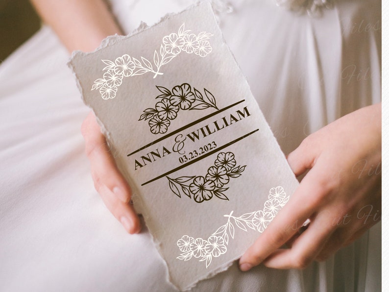 May include: A white card with a brown floral design and the text "ANNA & WILLIAM 03.23.2023" in a black banner.